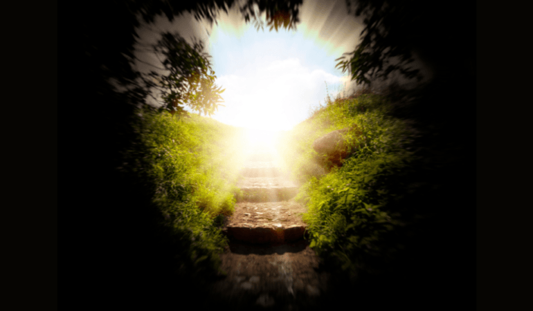 Stone stairway leading upward into bright sunlight through an archway of trees, symbolizing the journey from darkness into healing and light