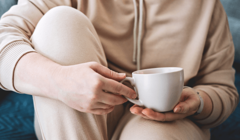 Person sitting with coffee cup in hand reflecting on her life